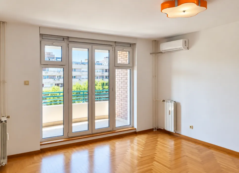 Empty room with parquet flooring, an air conditioning unit, and balcony doors leading to the terrace.