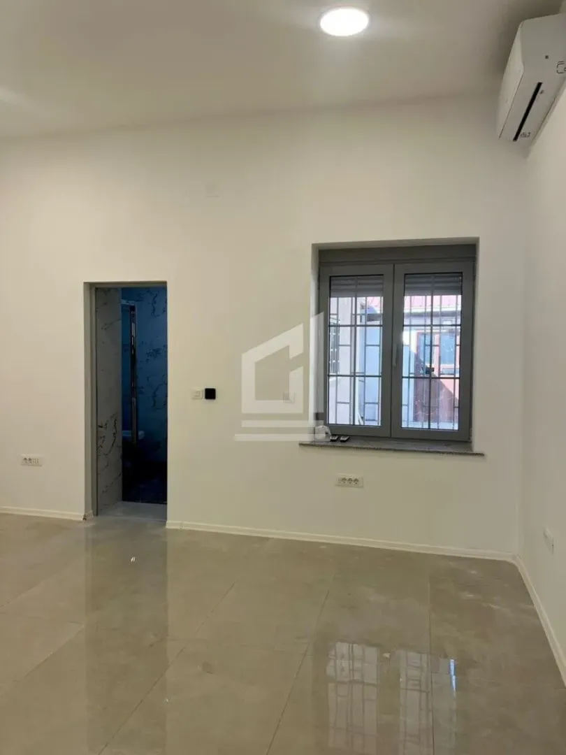 Empty room with a window, air conditioning unit, and a doorway leading to another bathroom.