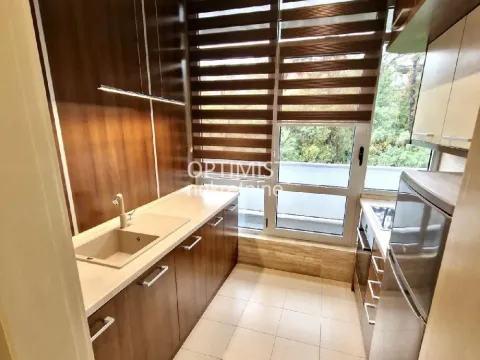 Small kitchen with wooden cabinetry, a sink, and a window with blinds. - image 3