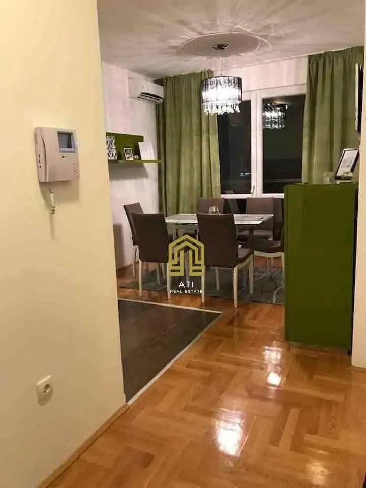Trpezarija sa stolom, stolicama i parketom na podu.