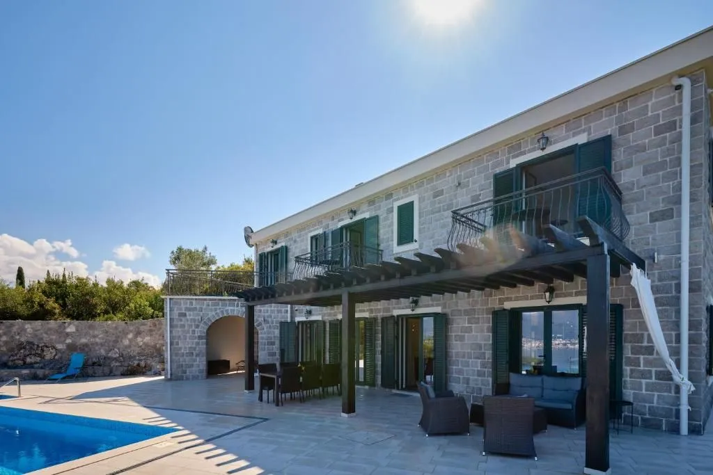 Exterior of a stone house with a swimming pool and terrace.