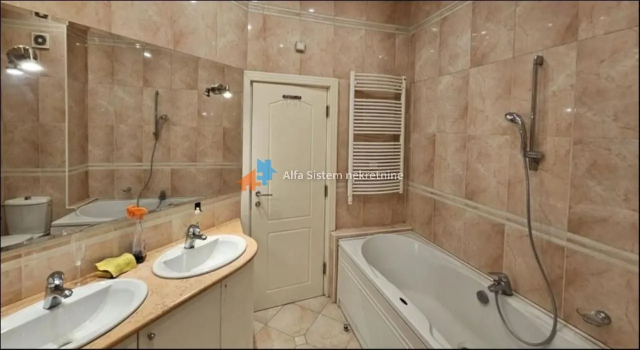 Tiled bathroom with a bathtub and double vanity sink.