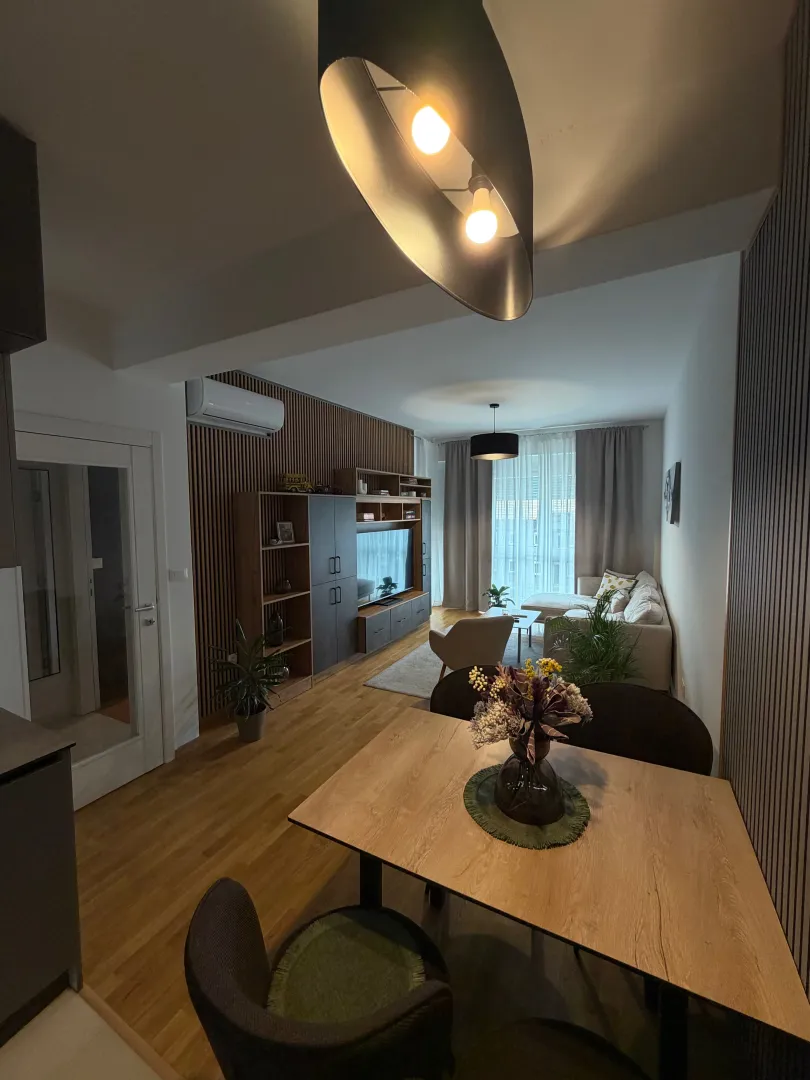 Modern living room with a dining area and wooden wall paneling.