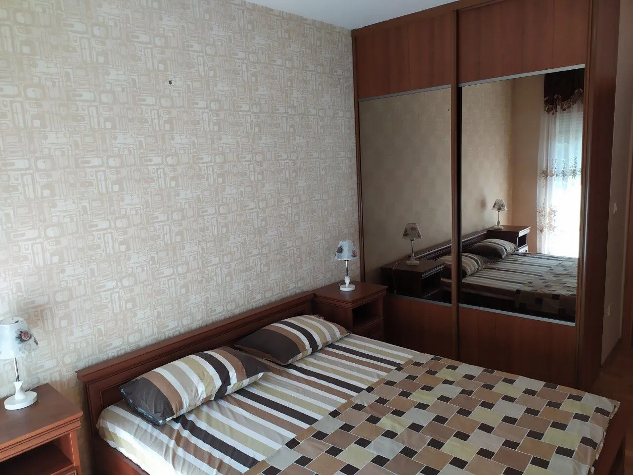 Bedroom featuring a double bed and a large wardrobe with mirrored sliding doors.