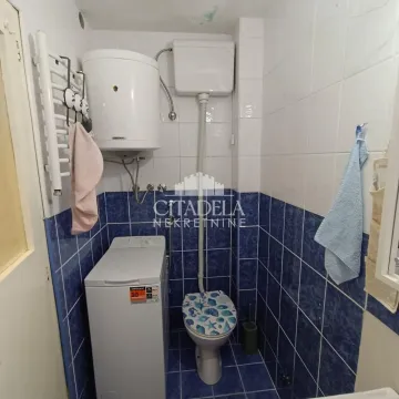 Manje kupatilo sa plavim pločicama, wc šoljom i veš mašinom. - image 3