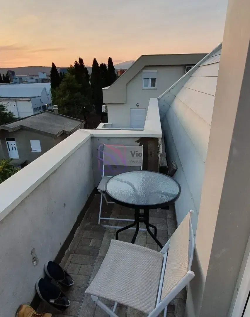 Manji balkon sa stolom i dve stolice i pogledom na okolinu.