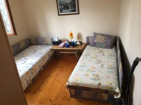 Dječija soba sa dva kreveta i drvenim podom.