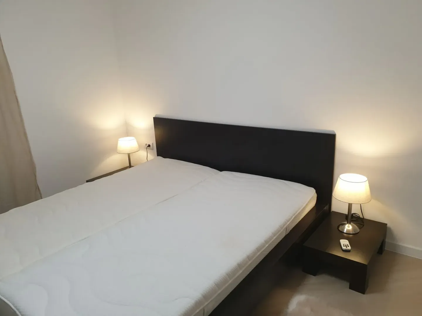 Spavaća soba sa bračnim krevetom i dve noćne lampe.