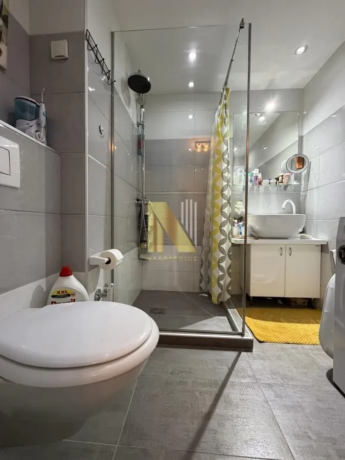 Savremeno opremljeno kupatilo sa tuš kabinom, umivaonikom i WC šoljom.