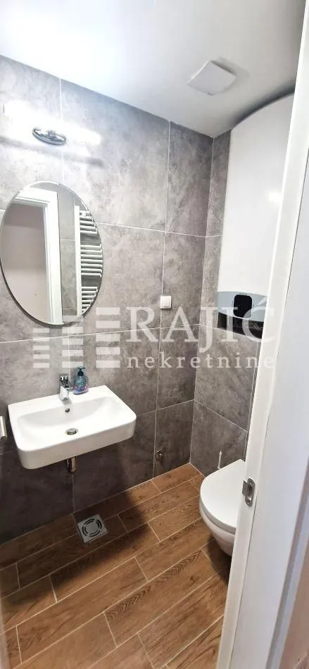 Smaller bathroom with a sink, toilet, and tiled walls.