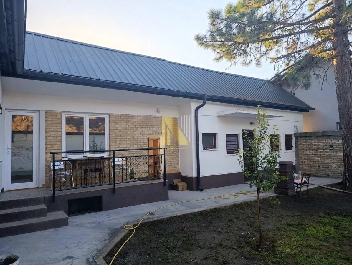 Pogled na dvorište i spoljašnjost prizemne kuće sa terasom.