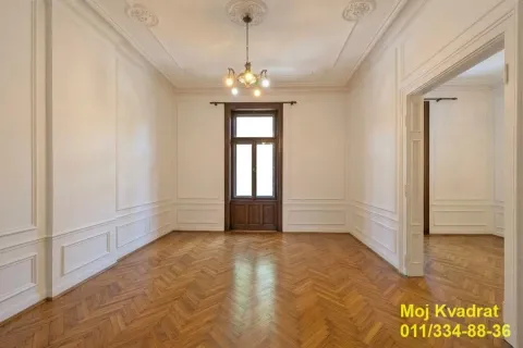 Prazna soba sa parketom, zidnim lajsnama i vratima koja vode na terasu. - image 4