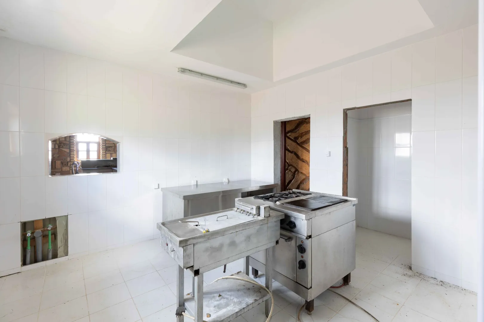 Commercial kitchen with stainless steel elements and white wall tiles.