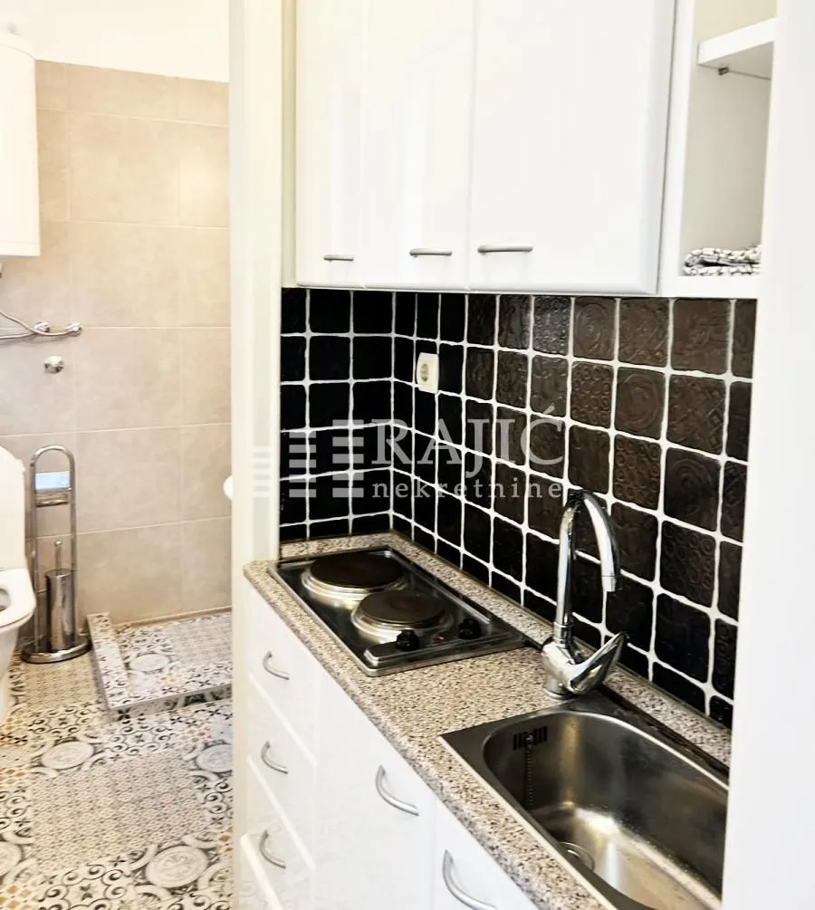Small kitchen combined with a bathroom in bright tones with white elements.