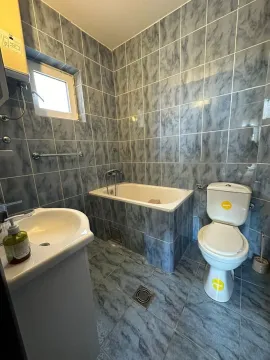 Manje kupatilo obloženo pločicama sa kadom, umivaonikom i toaletom. - image 16