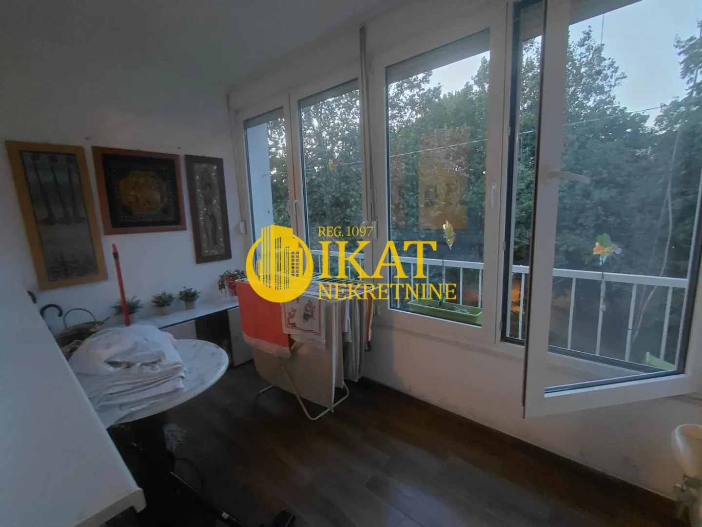 Enclosed balcony with large windows and a green view.