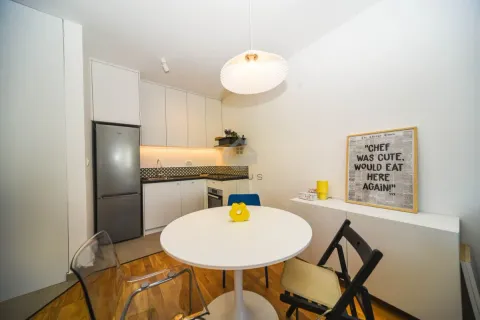 Smaller modern kitchen with a dining table and white elements. - image 9