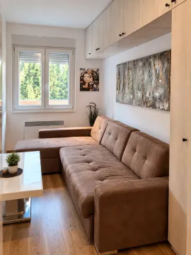 Living room with a corner sofa, coffee table, and wall-mounted storage cabinets. - image 2