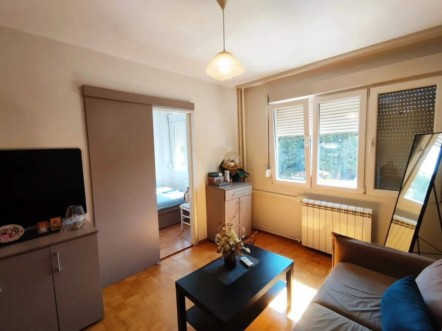 Dnevna soba sa garniturom, televizorom i pogledom na prozor.