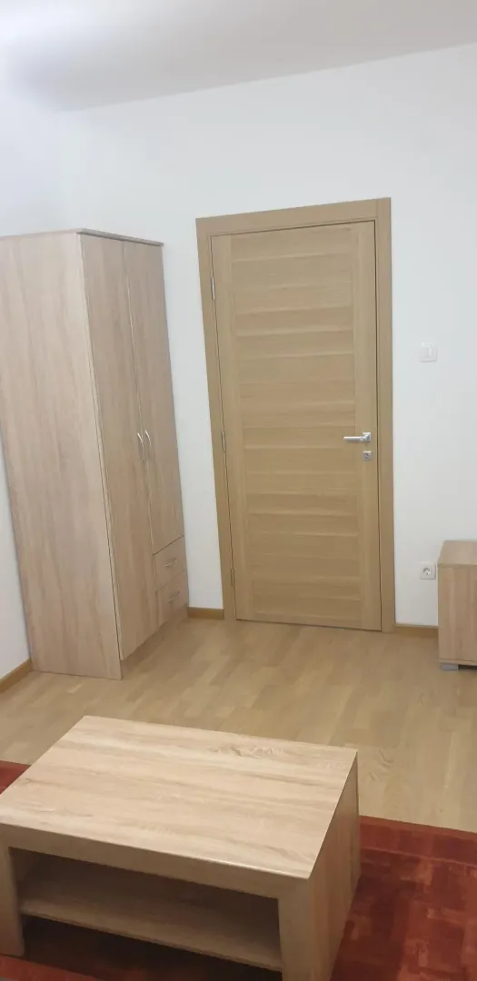 Jednostavna soba sa drvenim vratima i ormarom.