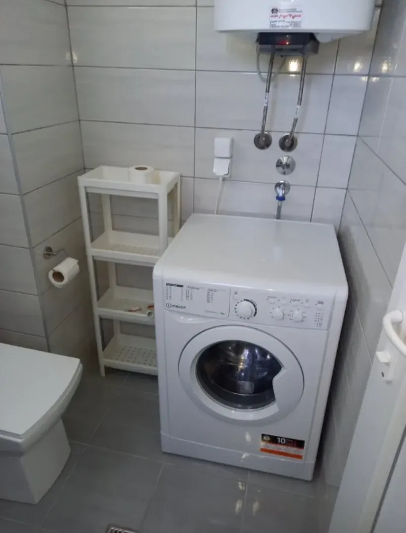 Manje kupatilo sa veš mašinom, bojlerom i toaletom.