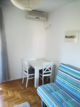 Mali trpezarijski sto sa dvije stolice i šarenim kaučem u sobi. - image 2