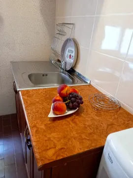 Part of the kitchen with a sink, countertop and a bowl of fruit. - image 7