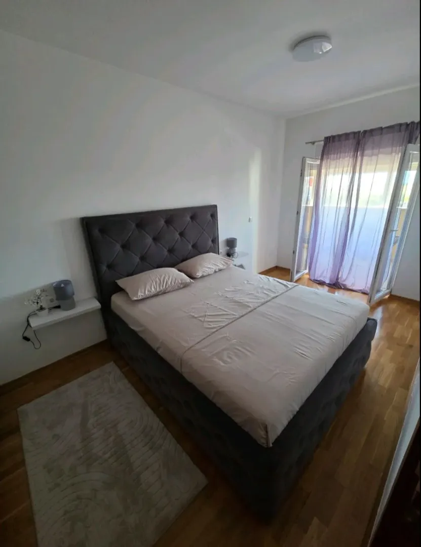 Uređena spavaća soba sa bračnim krevetom i izlazom na terasu.