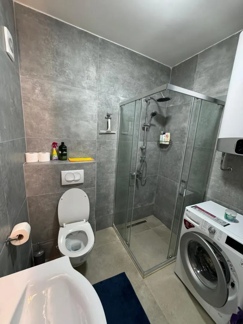 Modern equipped bathroom with a shower cabin and a washing machine.