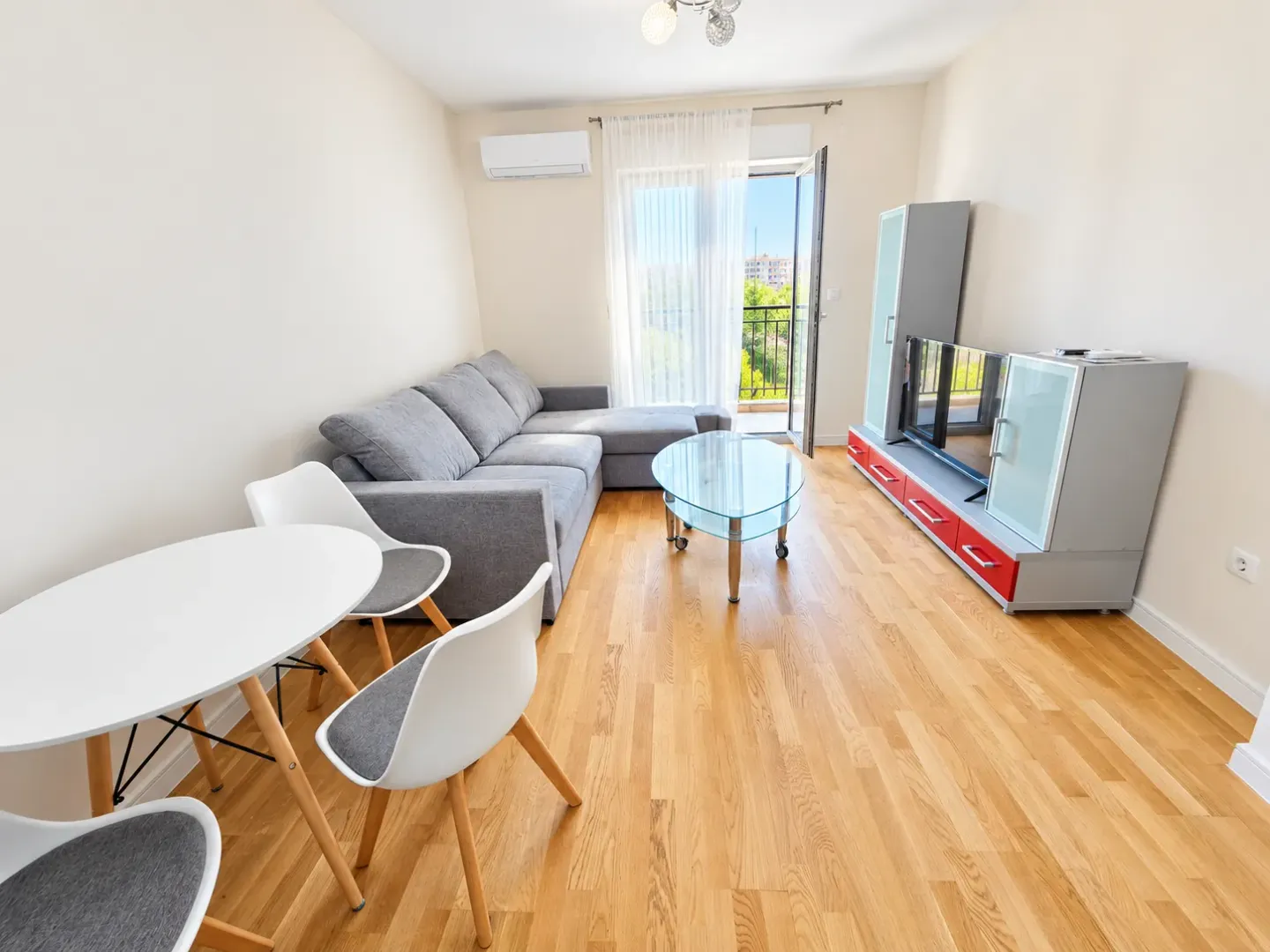 Living room with sofa, TV unit, and dining table.