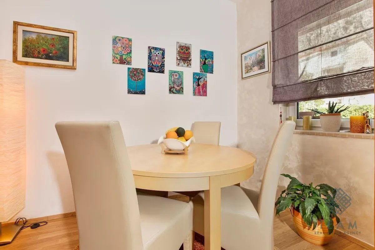 Dining table with chairs in the corner of the living room decorated with paintings.