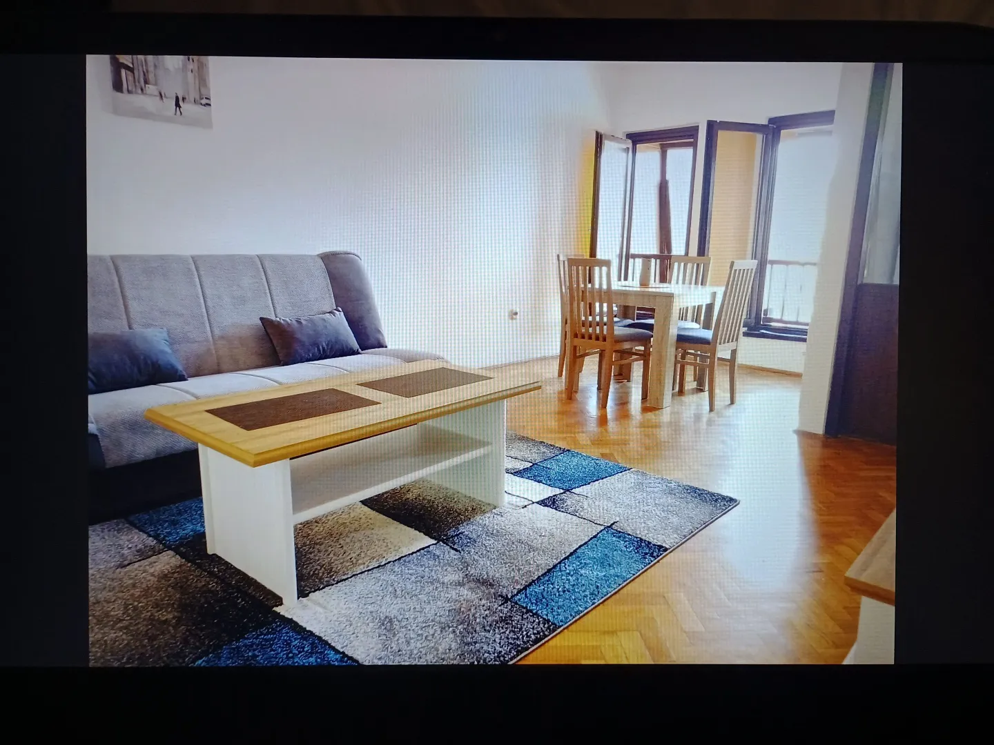 Dnevni boravak sa garniturom, stočićem i trpezarijom u pozadini.