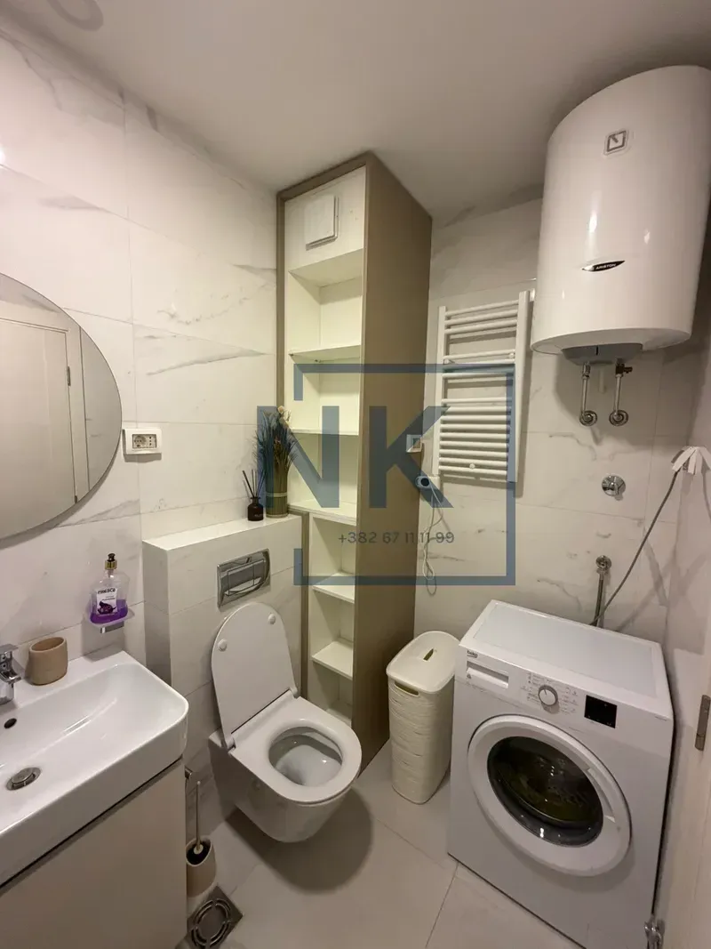 Compactly equipped bathroom with a washing machine, toilet, sink, and water heater.