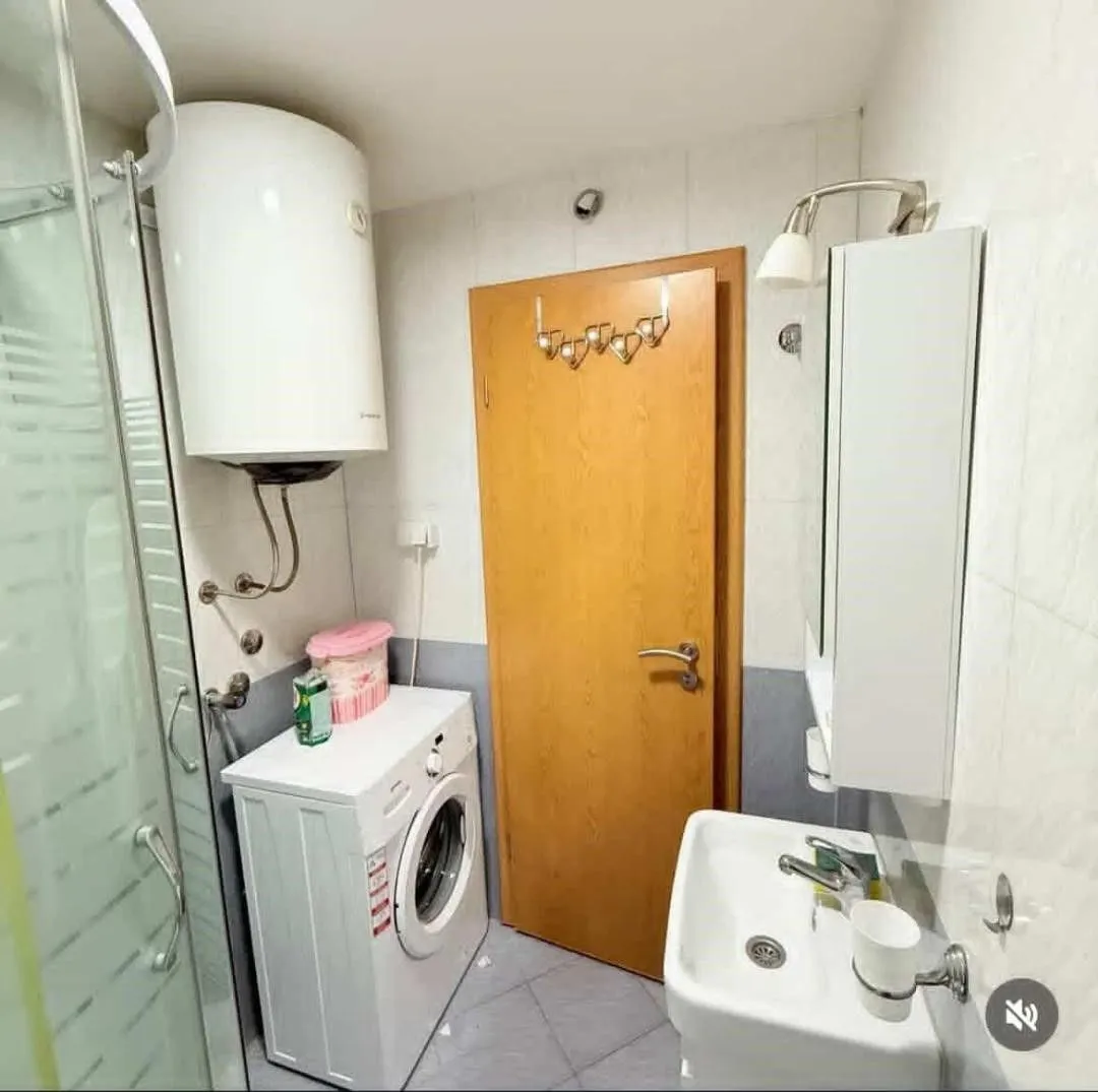 Compact bathroom with a shower cabin, washbasin, washing machine, and water heater.