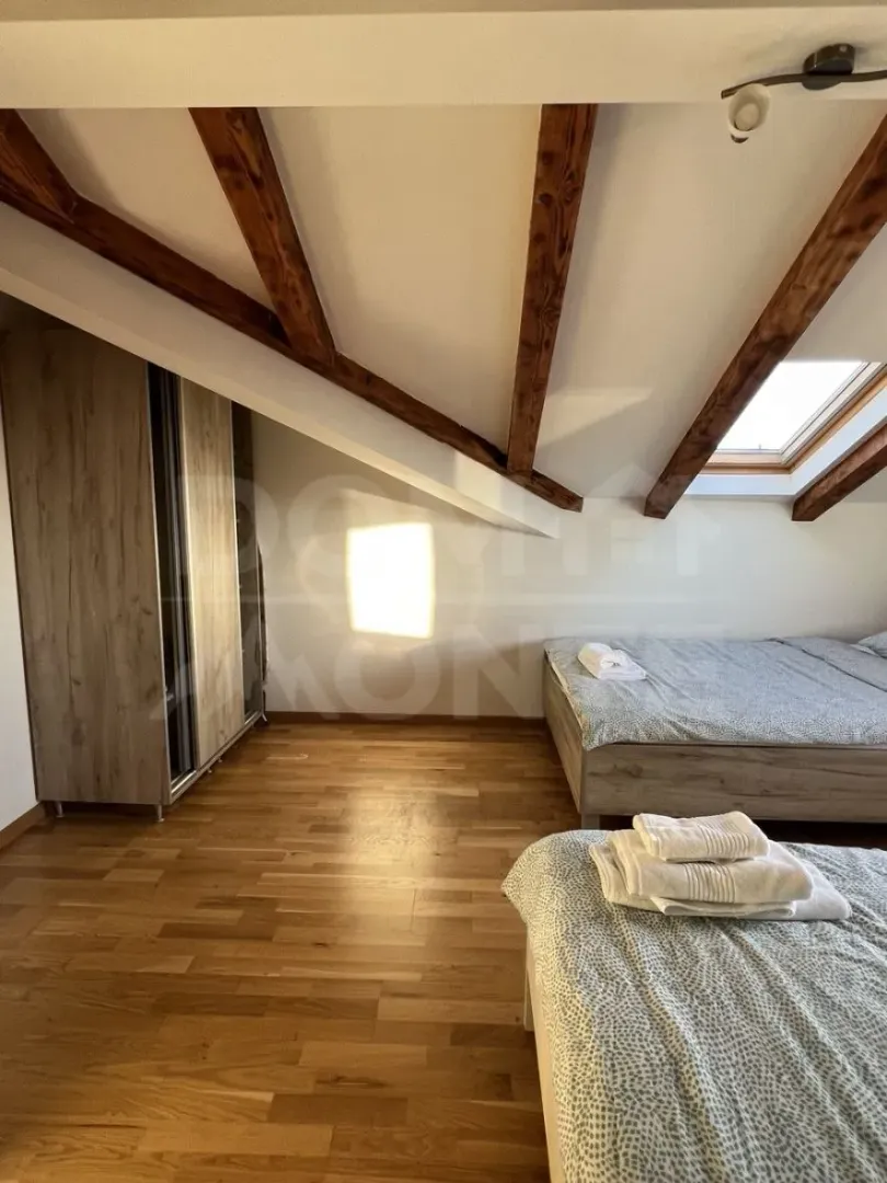Attic bedroom with wooden beams, beds, and a wardrobe.