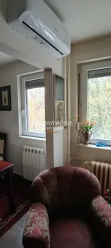 Deo dnevne sobe sa foteljom, klima uređajem i prozorima koji gledaju na zelenilo. - image 15