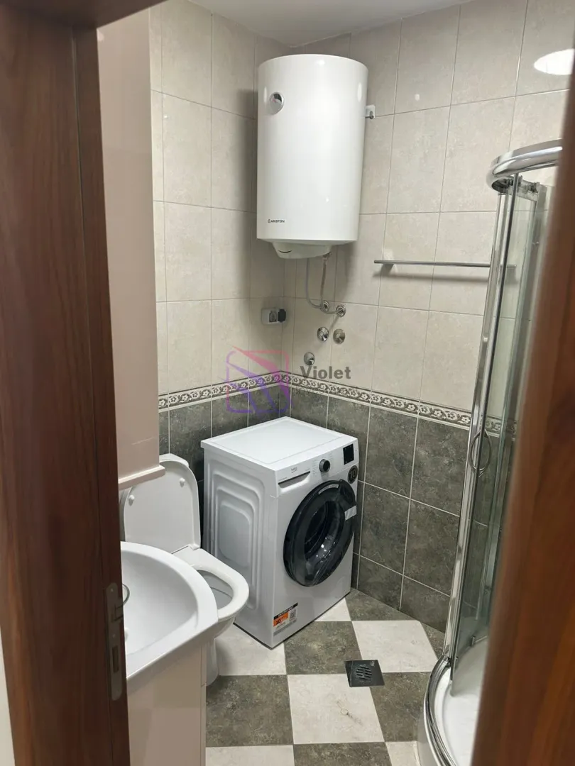 Bathroom with a shower cabin, washbasin, toilet, washing machine, and water heater.