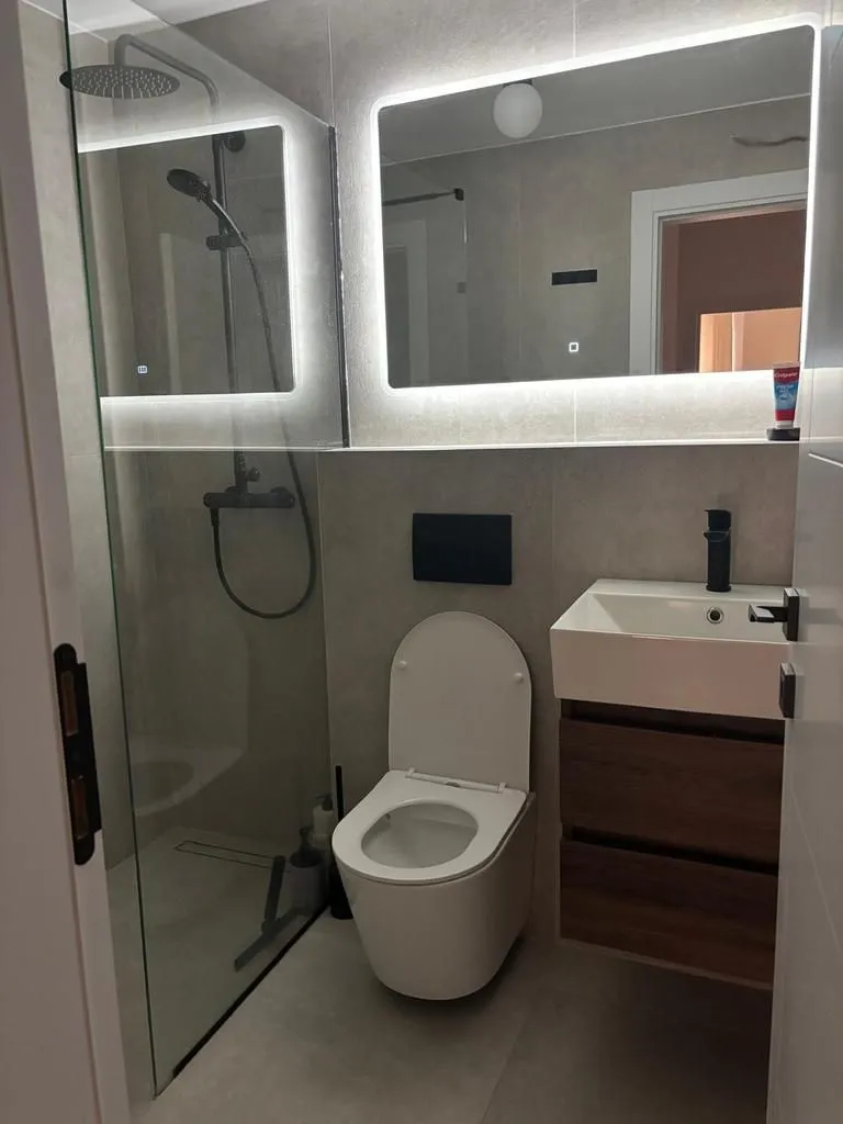 Moderno opremljeno kupatilo sa tuš kabinom, wc šoljom i umivaonikom.