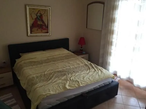 Svijetla spavaća soba sa bračnim krevetom i noćnim ormarićima.