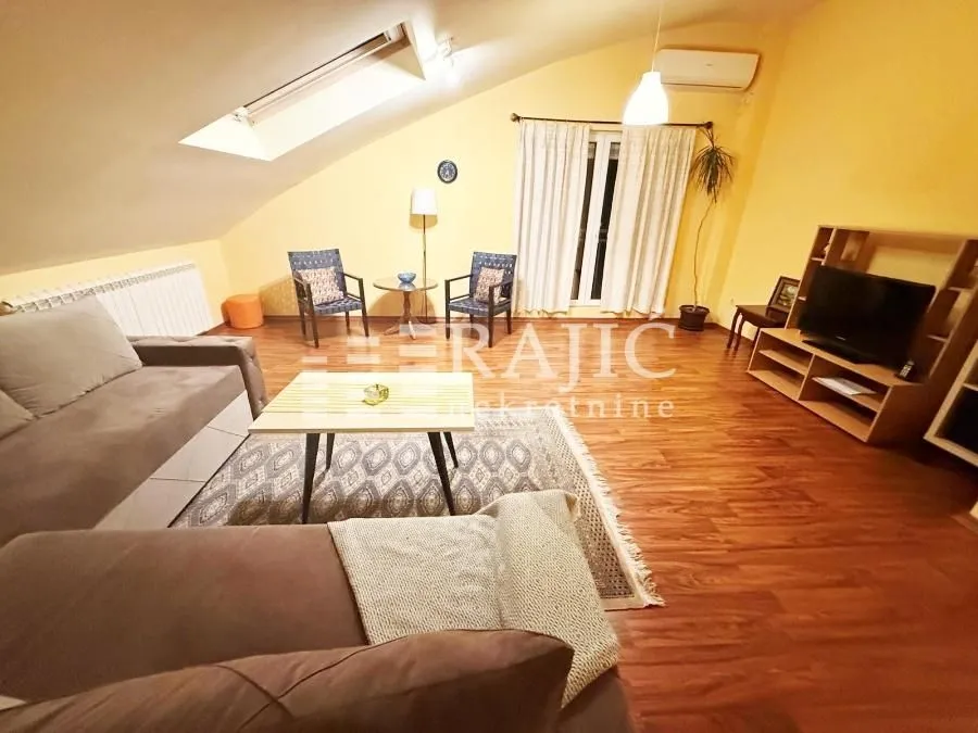 Furnished attic living room with a sofa set and TV unit.