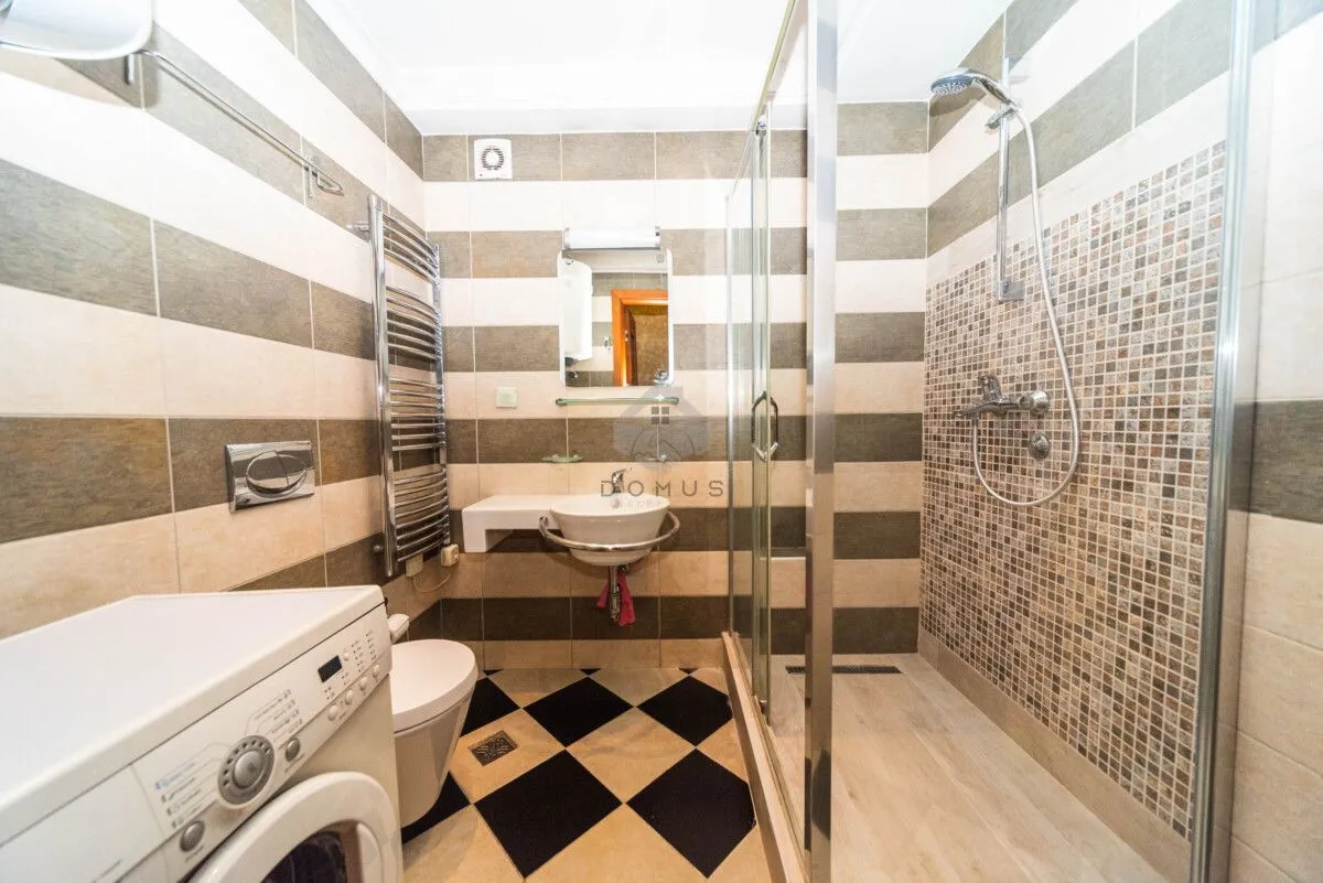 Bathroom equipped with a shower cabin, washbasin, toilet, and washing machine.