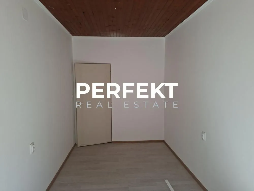 Prazna soba sa drvenim plafonom i svetlim laminatom.
