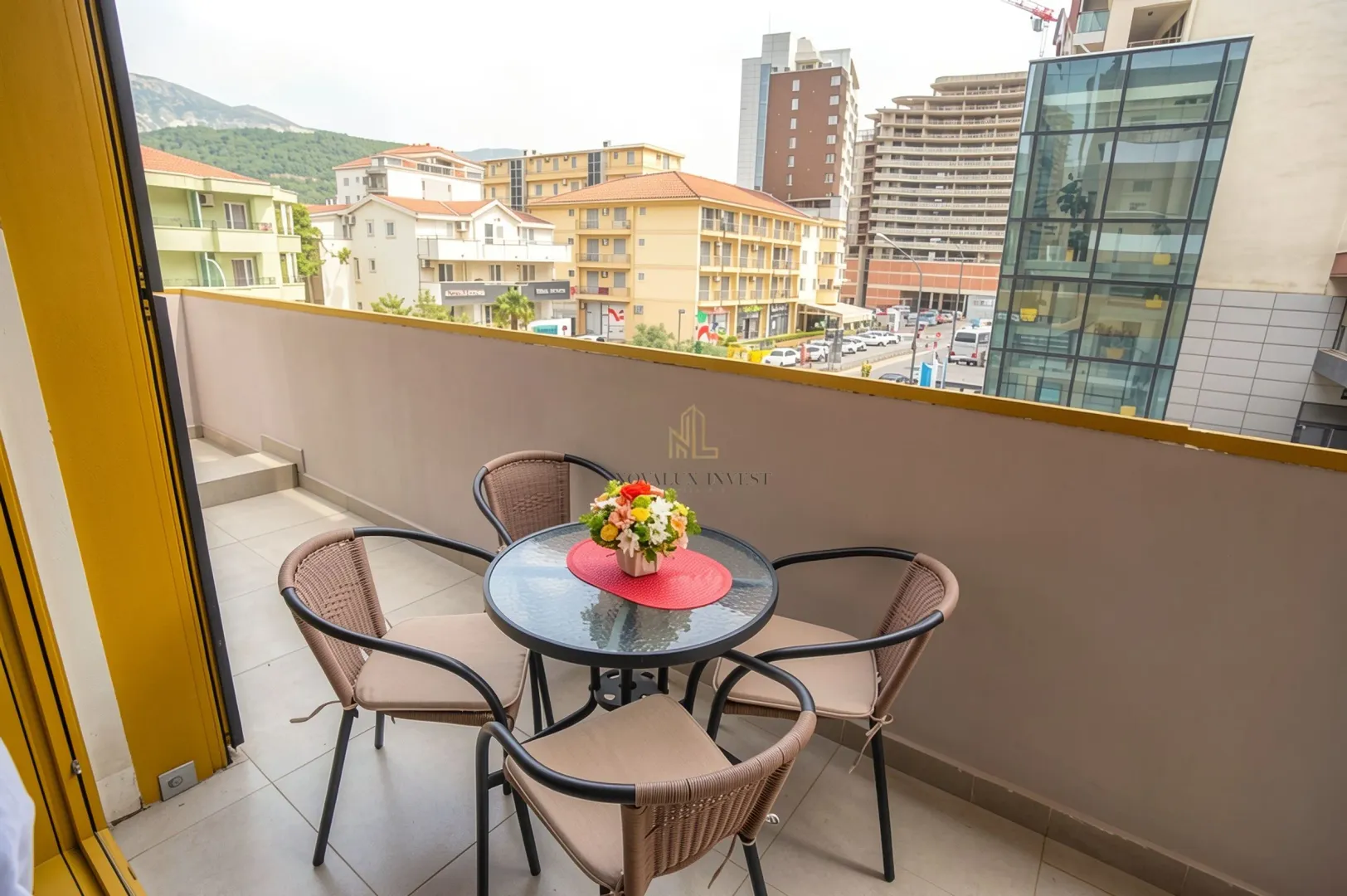 Furnished balcony area with a table and four chairs and a city view.