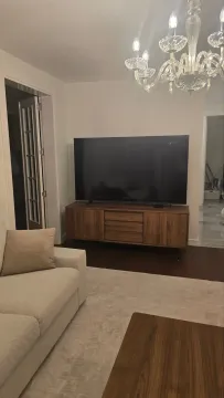 Living room with a sofa, TV console, and a large chandelier. - image 7