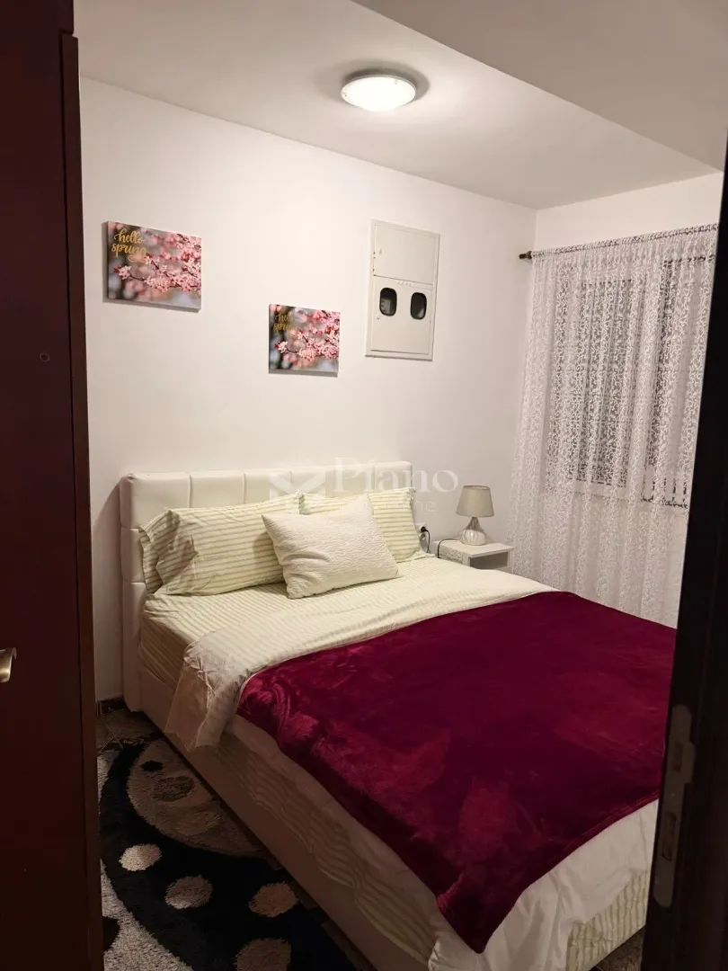 Bedroom with a double bed and a window with a white curtain.