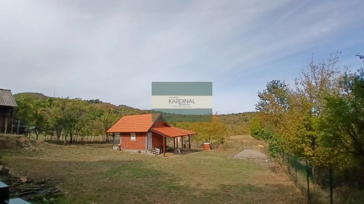 Pogled na manju kuću sa placem i prirodom u okruženju.