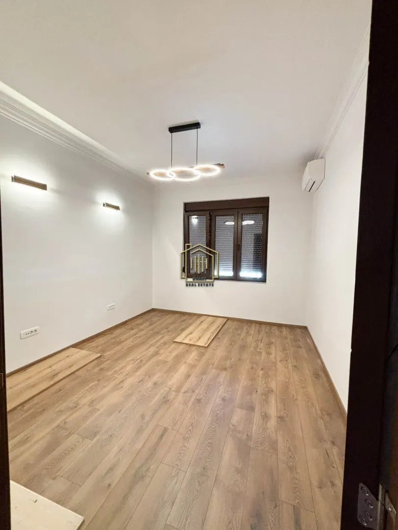 Empty room with wooden flooring, white walls, and a window.