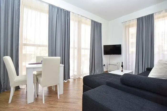 Living room with a sofa set, dining table and large windows.