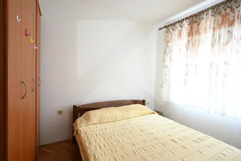 Furnished bedroom with a double bed, wooden wardrobe, and a window with curtains. - image 10