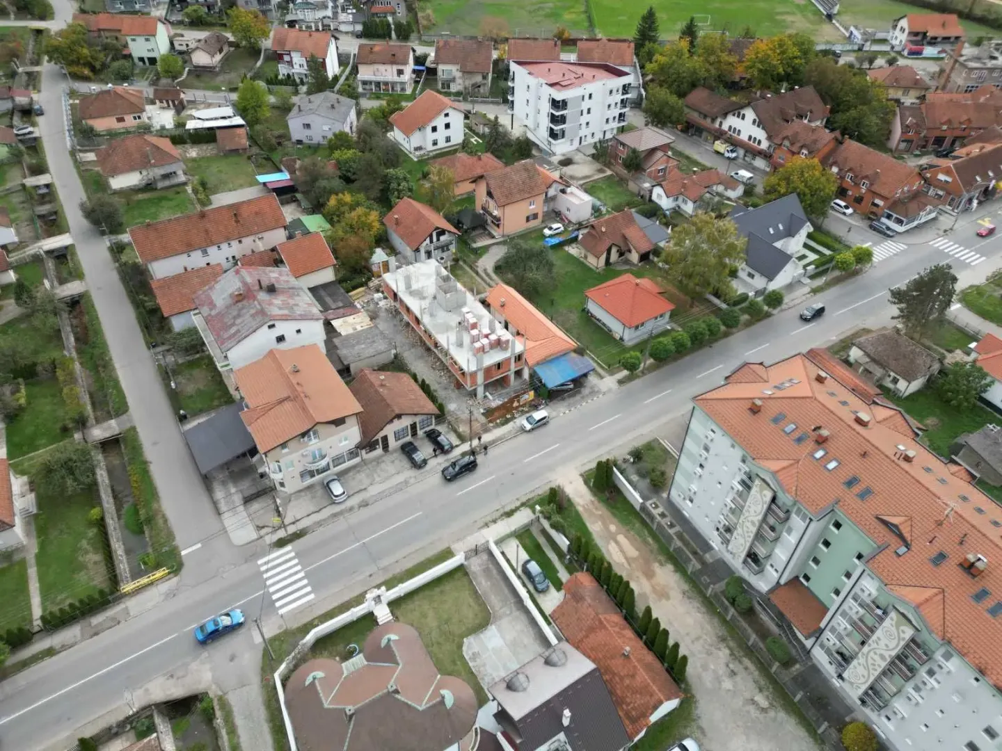 Pogled iz vazduha na naselje sa porodičnim kućama i zgradama.